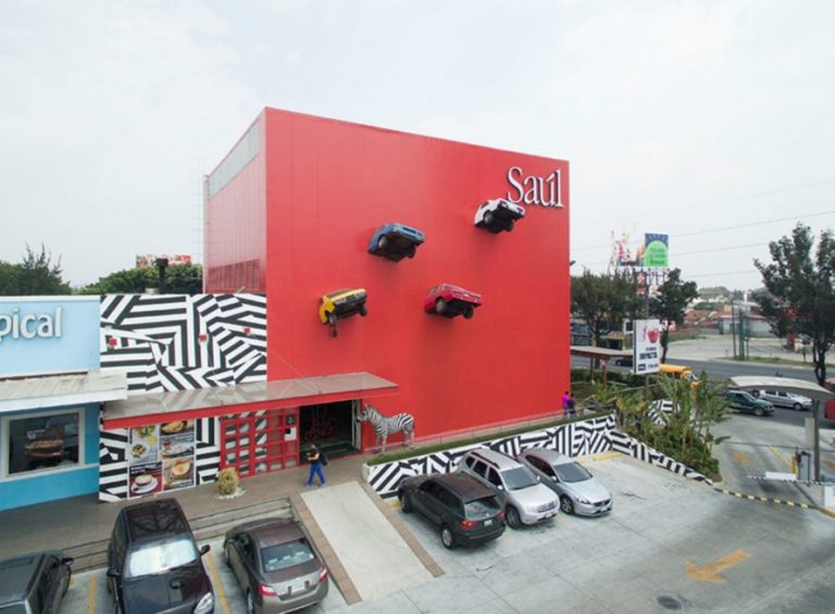 咖啡馆的外观建筑上有4辆颜色迥异的老爷车“破墙而出”。(图片来源:Leonardo Izaguirre)